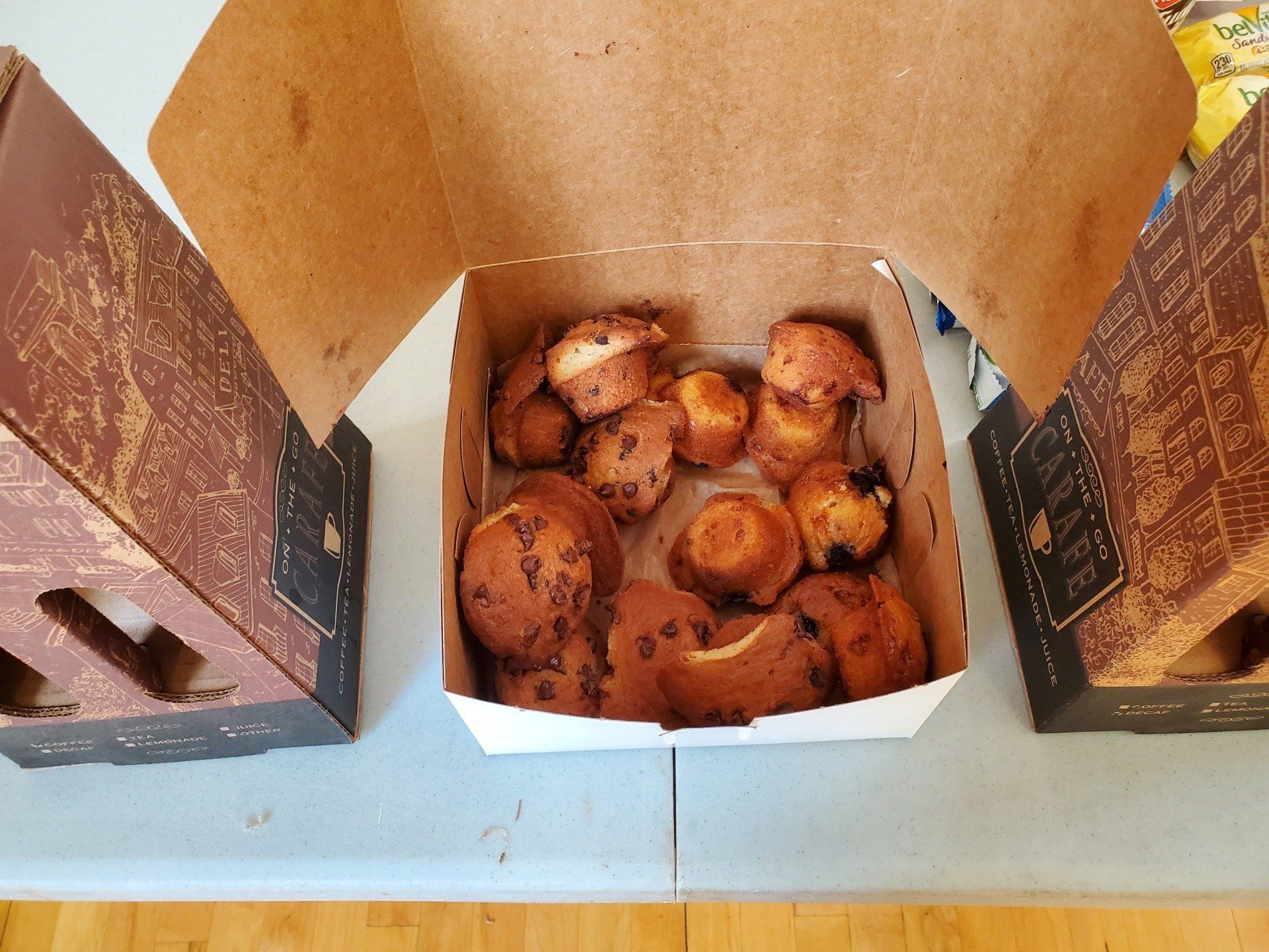 A box of donuts sits on a table next to two other boxes