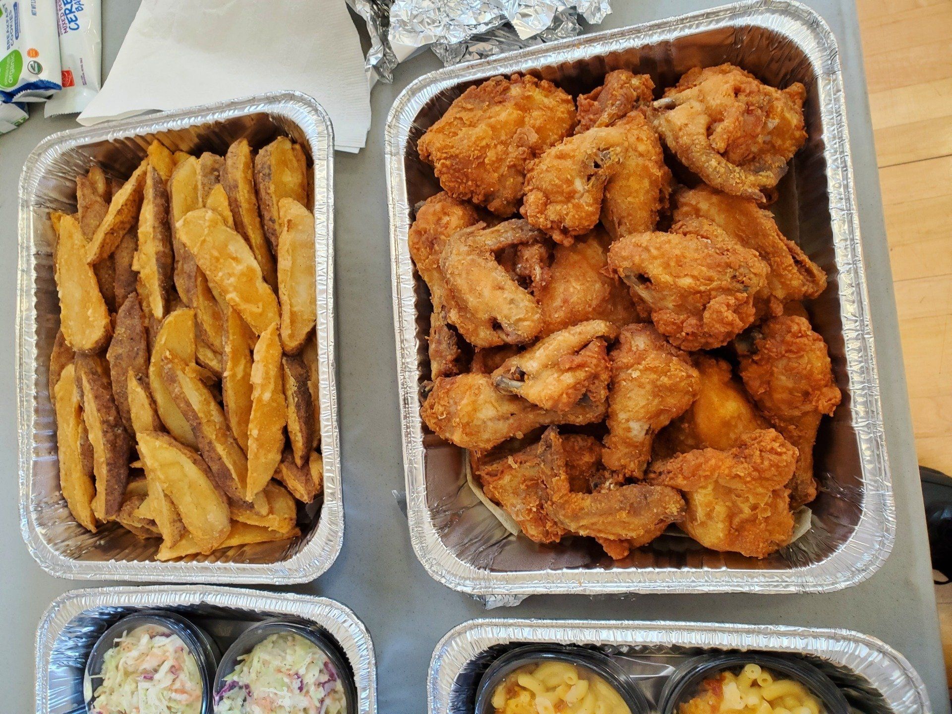 Aluminum foil containers filled with fried chicken , french fries , macaroni and cheese , and coleslaw.