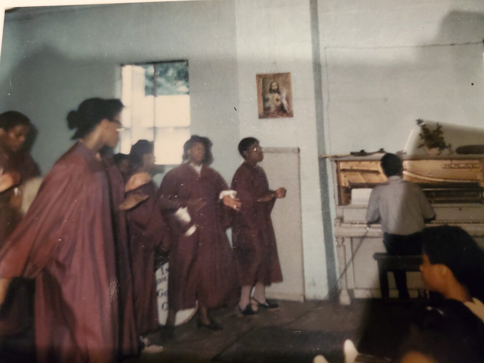 A group of people standing in a room with a man playing a piano