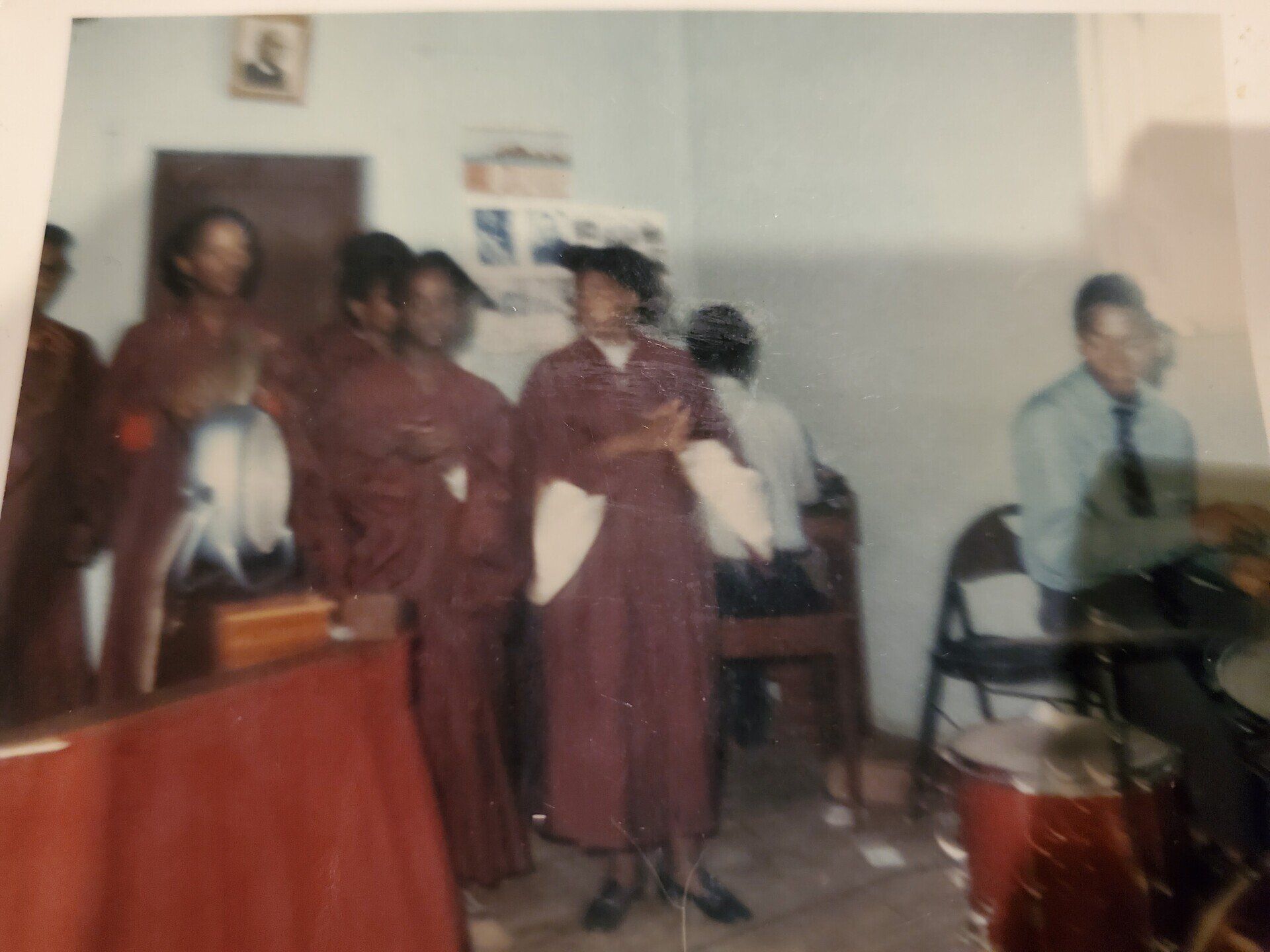 A group of people are standing in a room and one of them is wearing a graduation cap and gown
