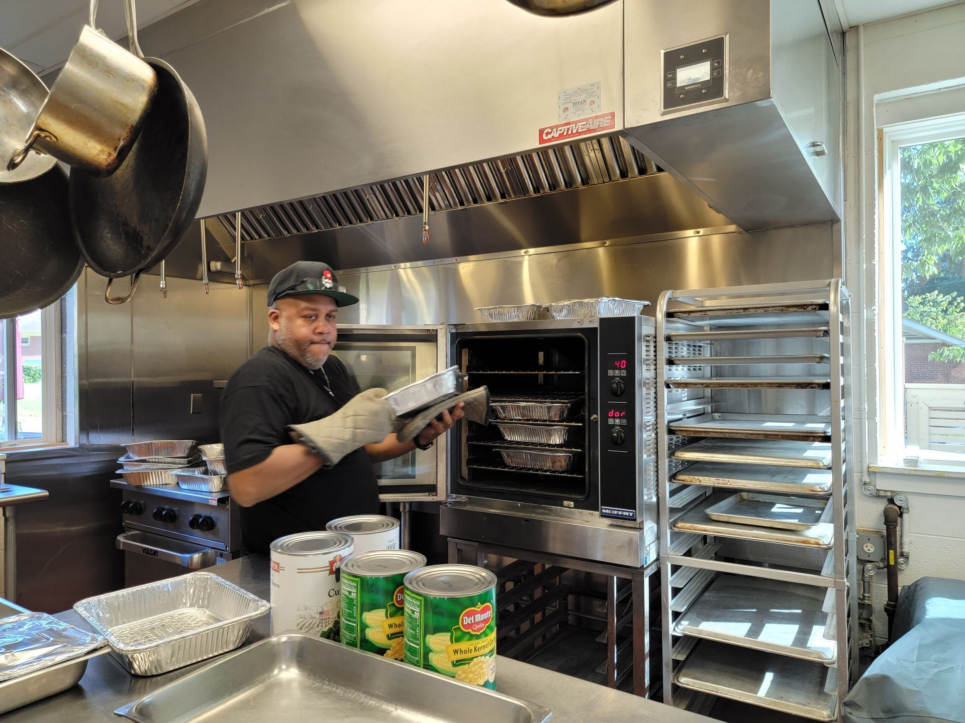 A man is standing in a kitchen holding a pan in front of an oven.