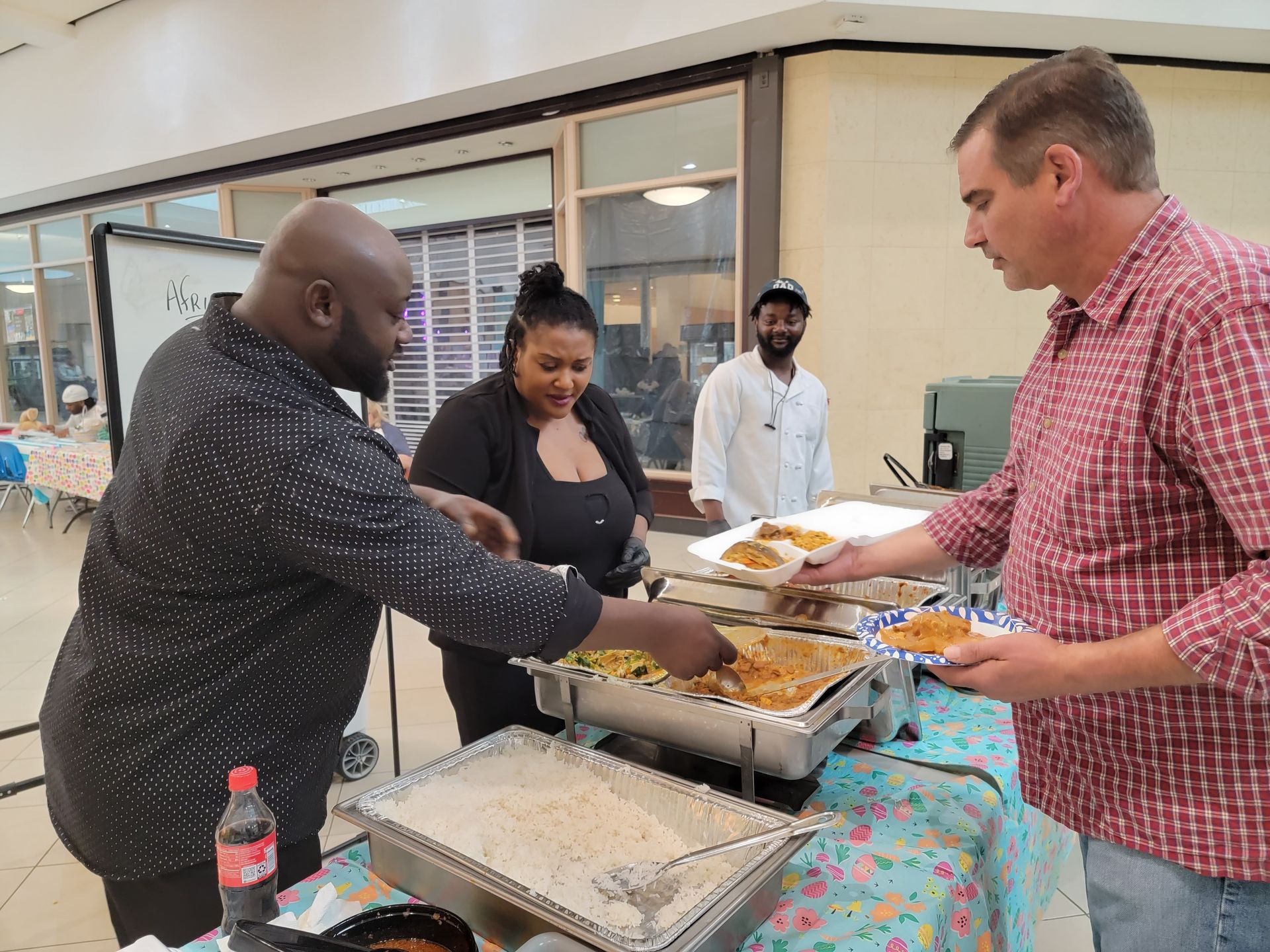 A group of people are standing around a table eating food.