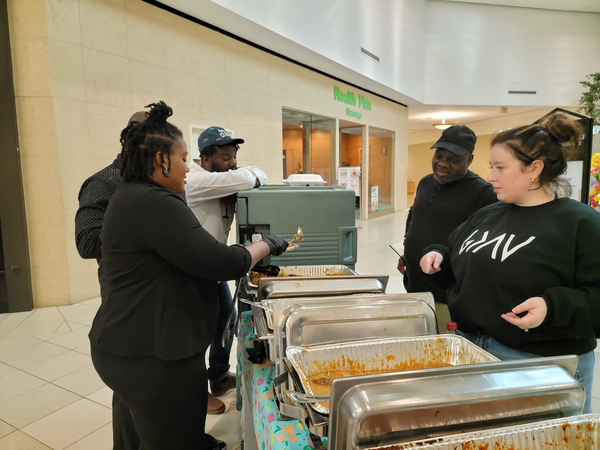A group of people are standing around a buffet line in a mall.