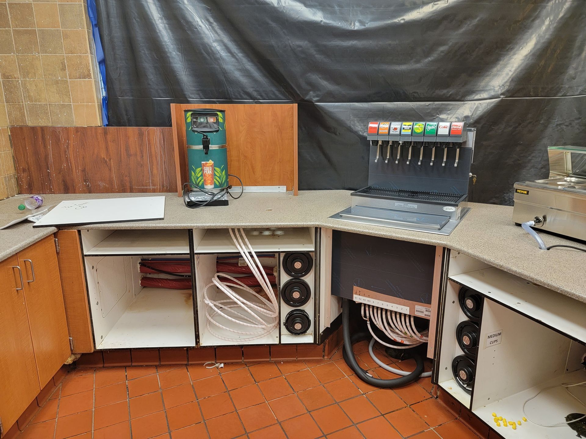 An empty kitchen with a soda fountain and a vacuum cleaner.