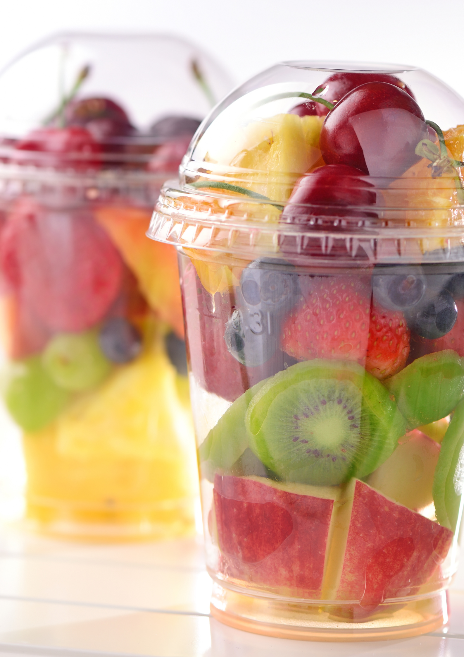 Two plastic cups filled with fruit on a table