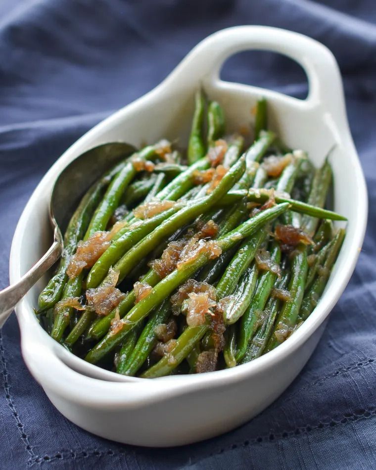 A bowl of green beans with a spoon in it