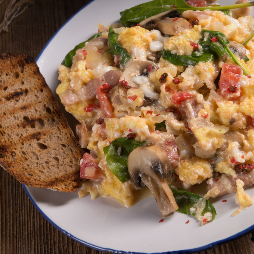 A plate of food next to a bowl of salad and a glass of orange juice.
