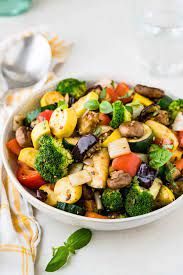 A white bowl filled with vegetables and a spoon on a table.