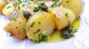 A white plate topped with potatoes , olives and parsley.