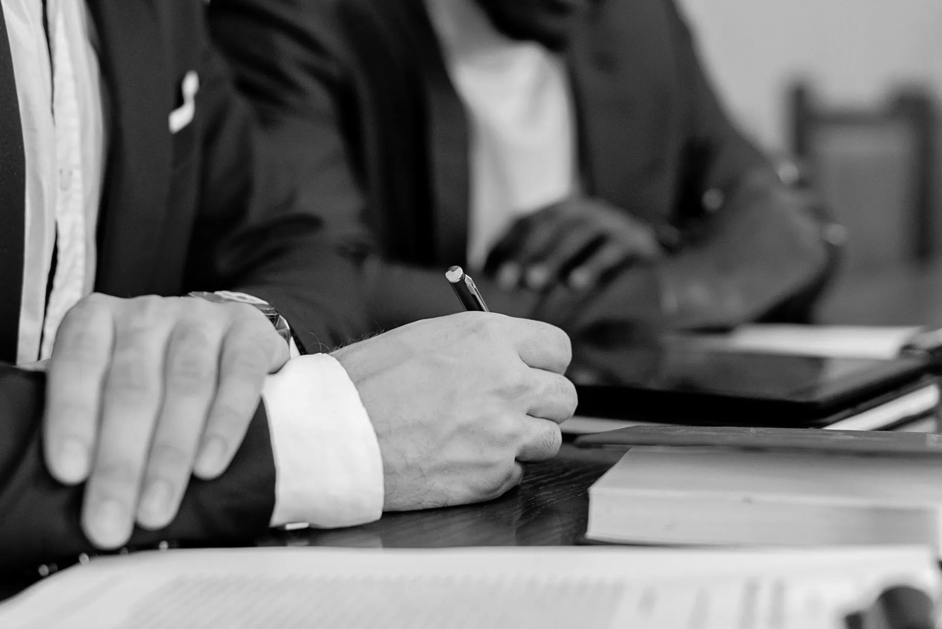 A man is sitting at a table writing on a piece of paper.