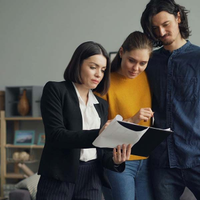 Three coworkers review a document together in a modern office.