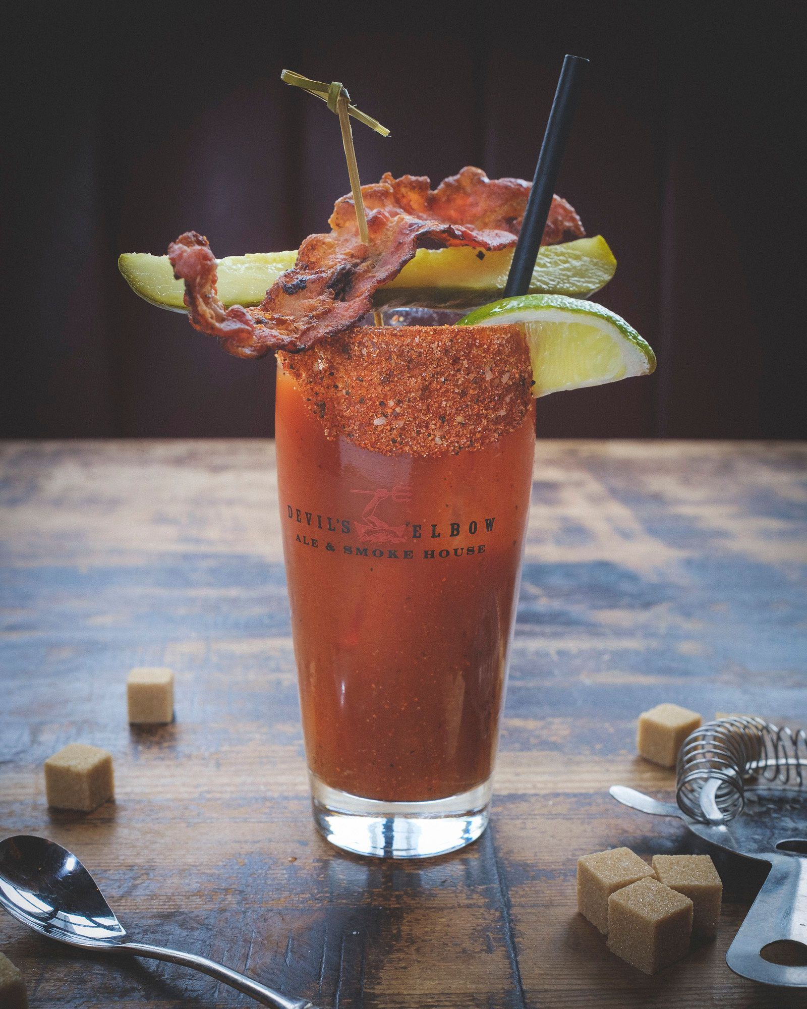 Bloody Mary cocktail with bacon, lime, and pickle garnish at Devil's Elbow bar in Vancouver.