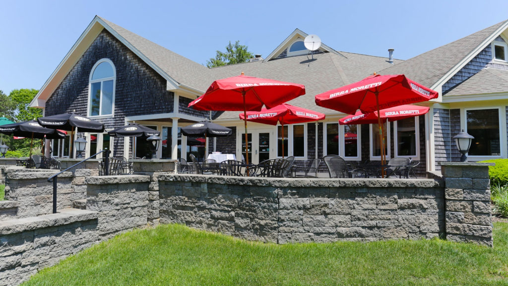 A house with red umbrellas and tables in front of it