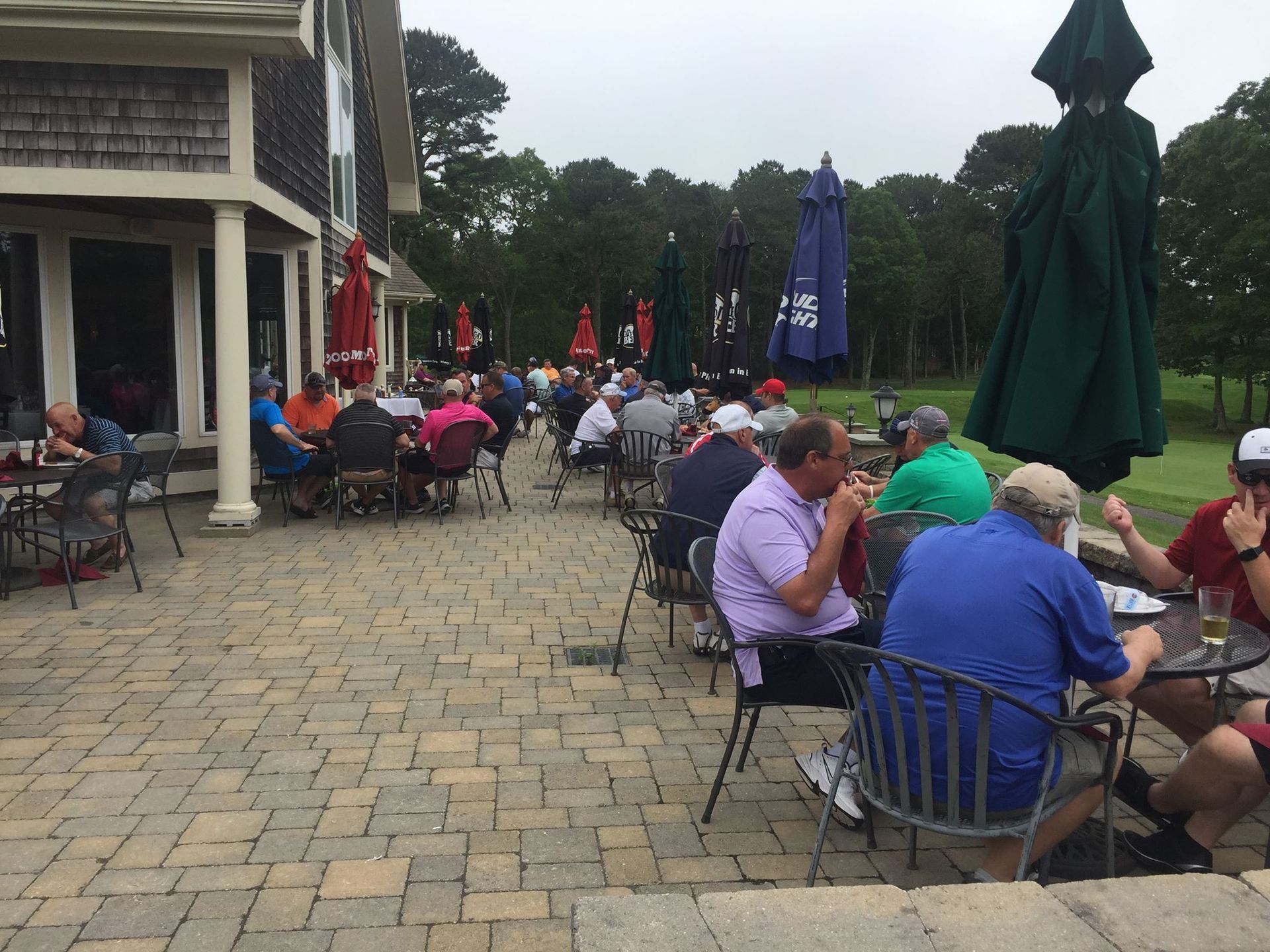 A group of people are sitting at tables outside on a patio.