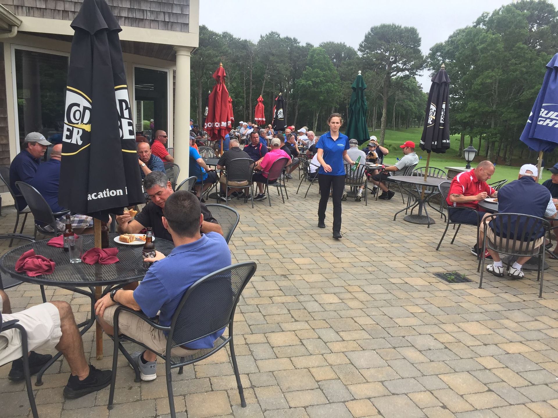A group of people are sitting at tables under umbrellas at a restaurant.