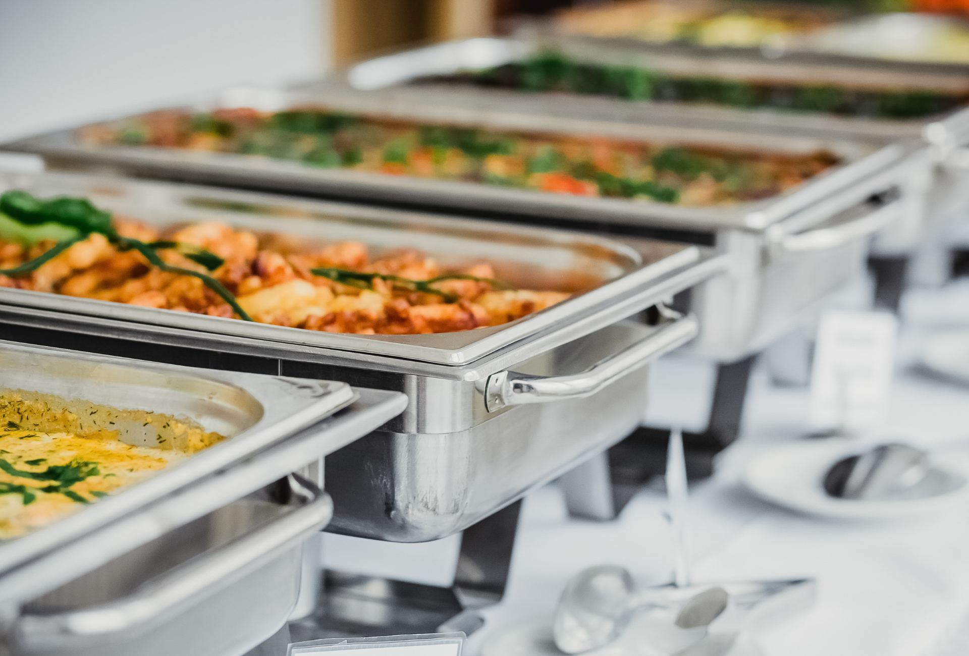 There are many trays of food on the table.