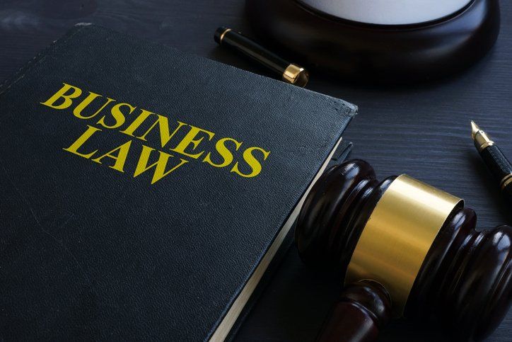 A book titled business law is on a table next to a judge 's gavel and a pen.