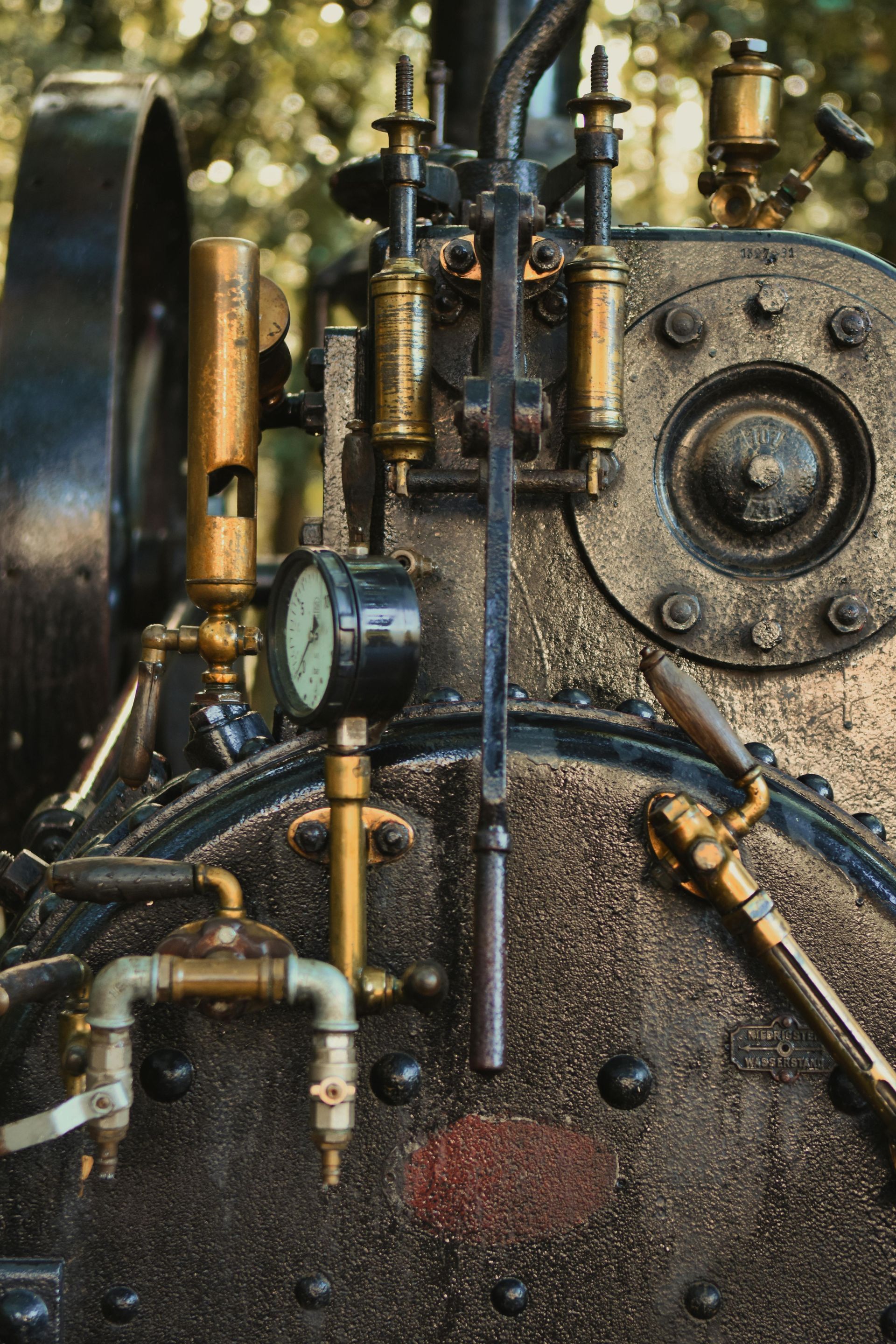 Close-up of a factory steam boiler with brass pipes, gauges, and a large black oil boiler.