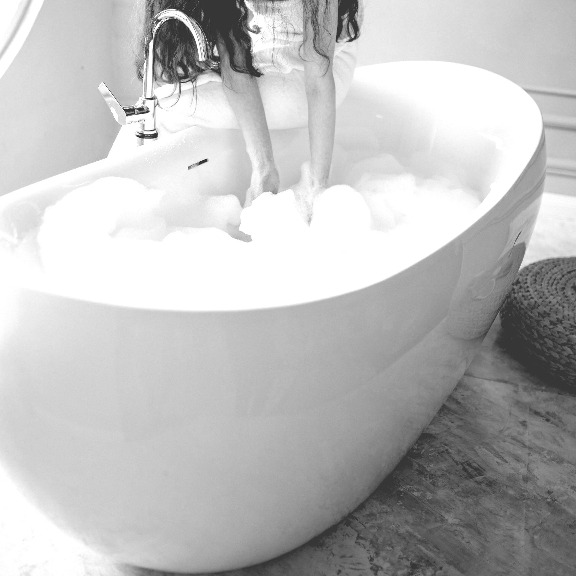 A woman is standing in a bathtub filled with foam.