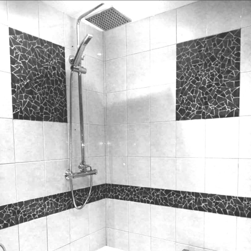 A black and white photo of a shower plumbing in a bathroom