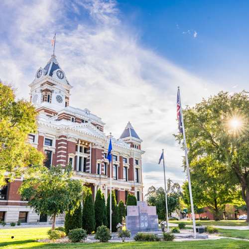 A large brick building with a clock tower and flags in front of it.