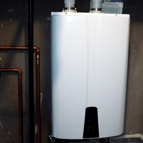 A white water heater is sitting next to copper pipes
