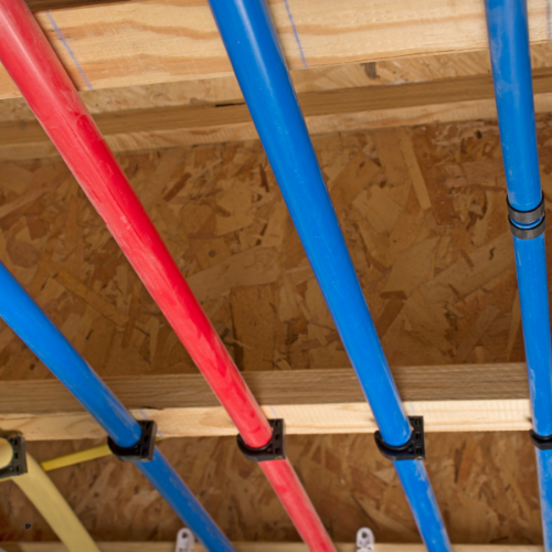 A bunch of blue and red pipes are hanging from the ceiling