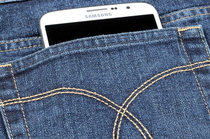 White Samsung phone partially in a blue jeans pocket.