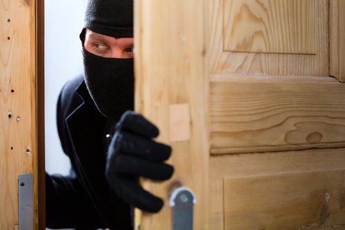 Burglar opening a door — Cerritos, CA — Southern California Security Centers Inc