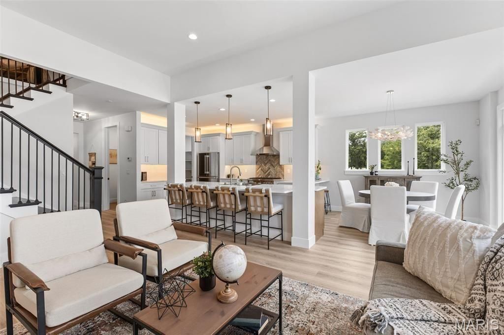 A living room with a lot of furniture and a staircase in the background.