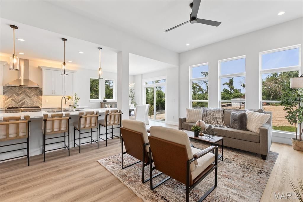 A kitchen with white cabinets and stools and a large island.