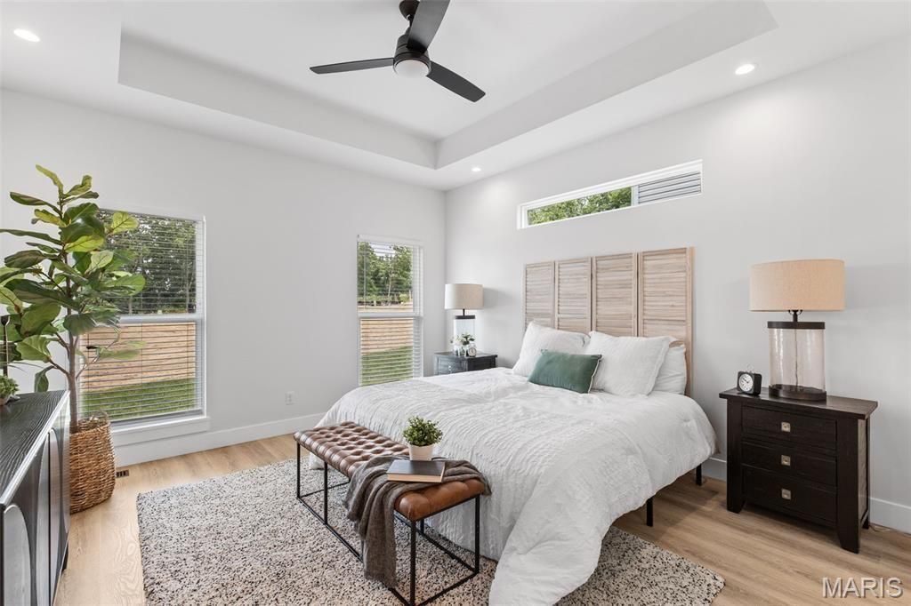 A bedroom with a bed , chair , nightstand and ceiling fan.