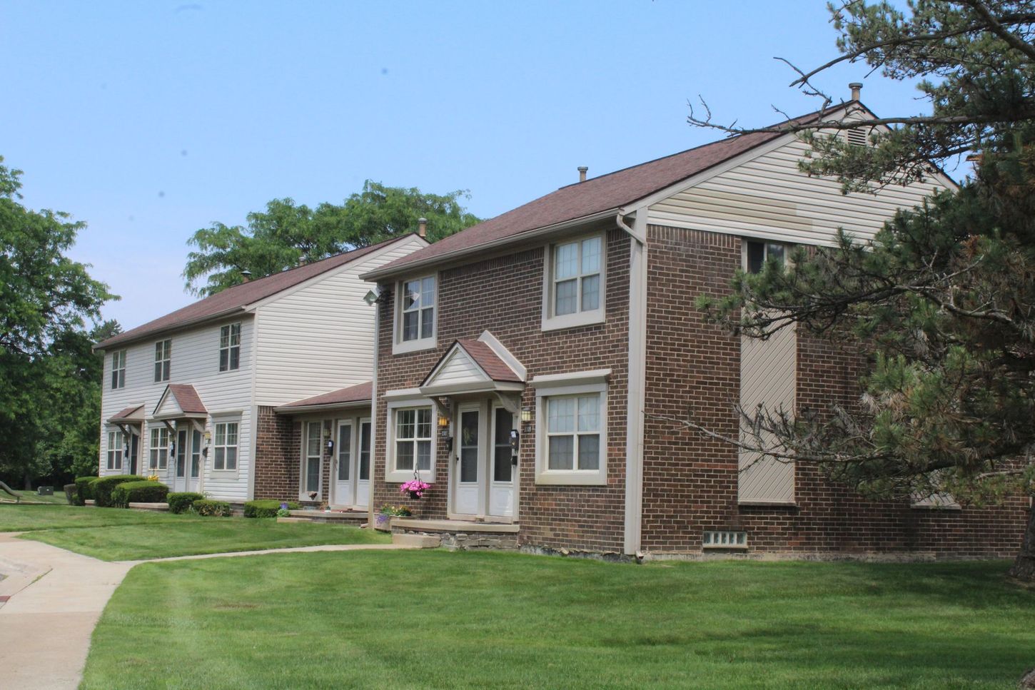 A row of apartment buildings with a lush green lawn in front of them