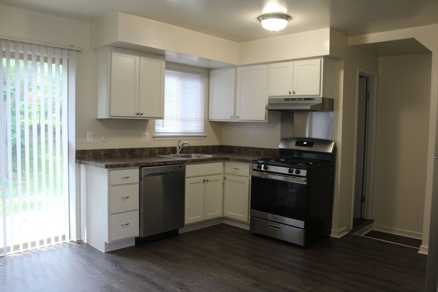 A kitchen with white cabinets , stainless steel appliances , a sink , and a stove.