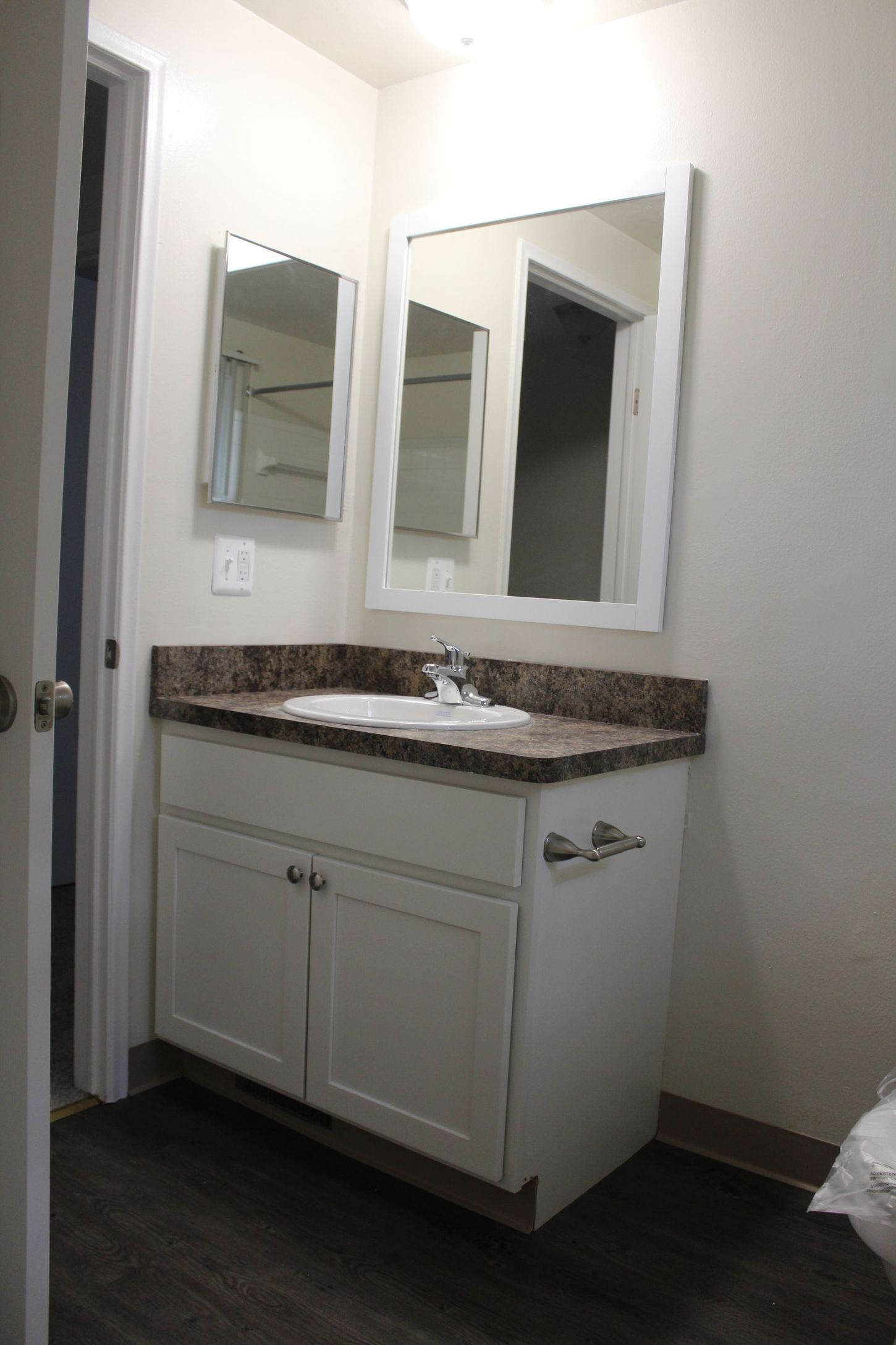 A bathroom with a sink and two mirrors.