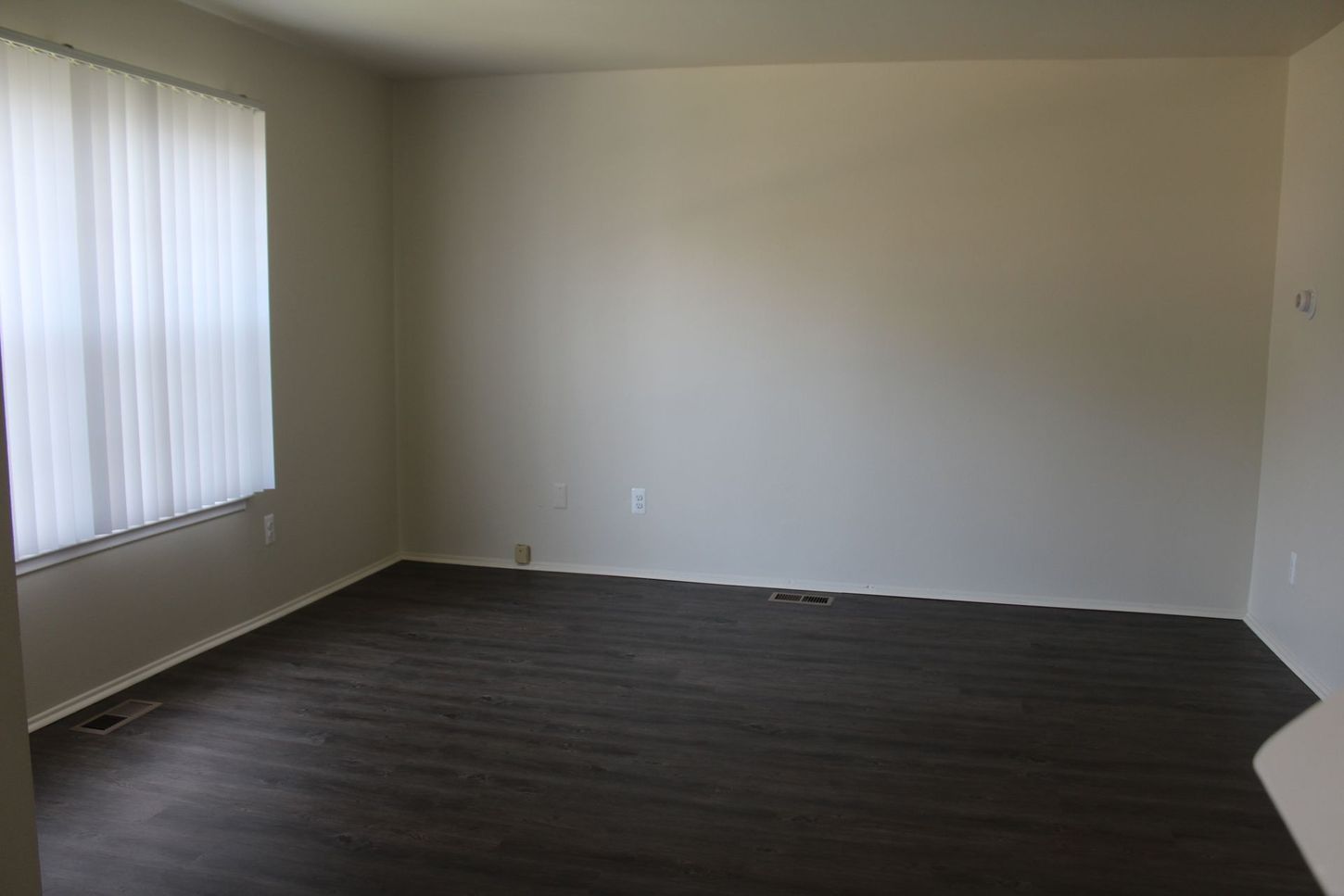 An empty living room with hardwood floors and a window.