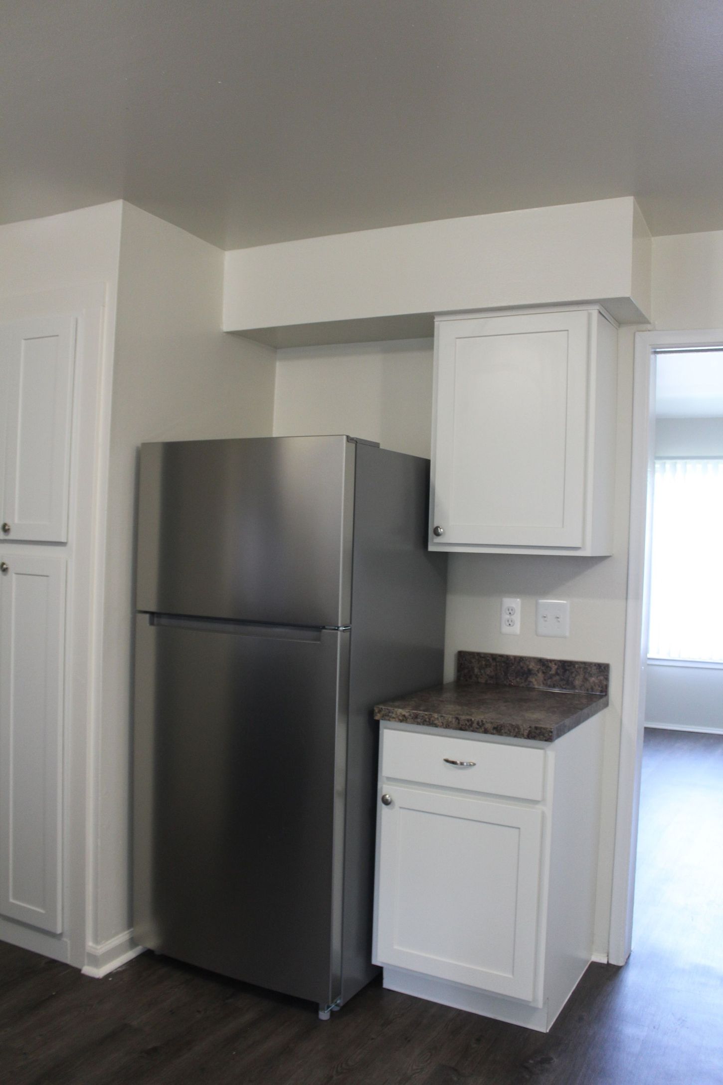 A kitchen with a stainless steel refrigerator and white cabinets.