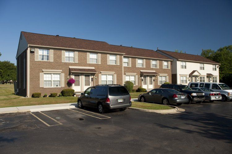 Several cars are parked in front of a brick apartment building