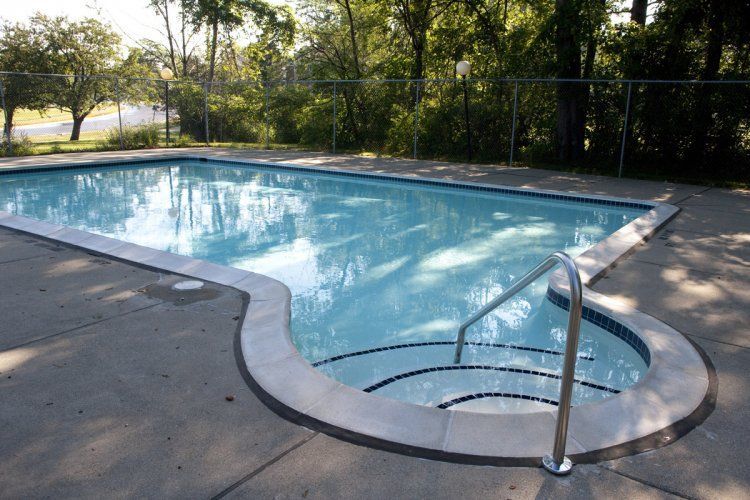 A swimming pool with stairs leading to it and trees in the background.