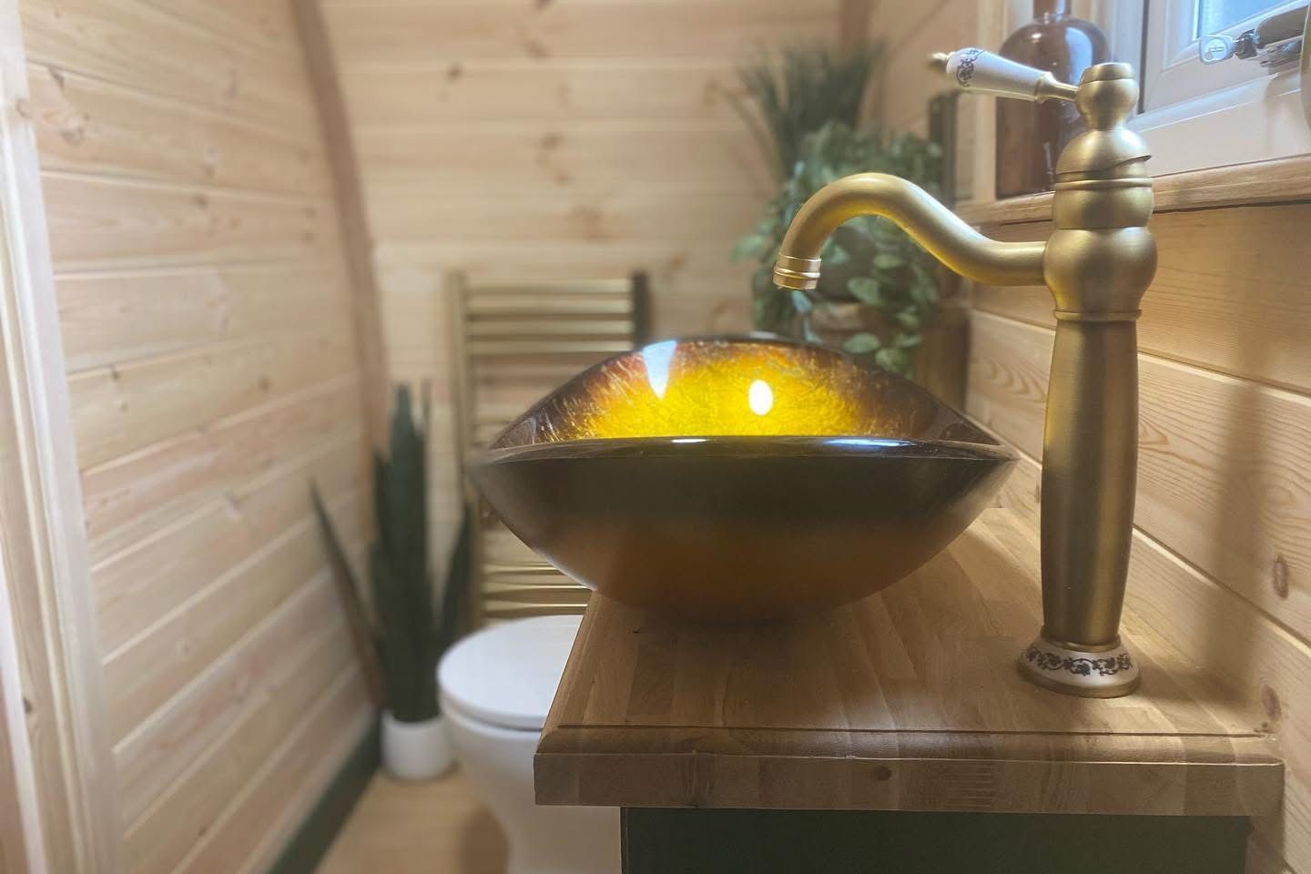 Glowing orange glass bowl with water fountain on a wooden counter in a small sauna-like room