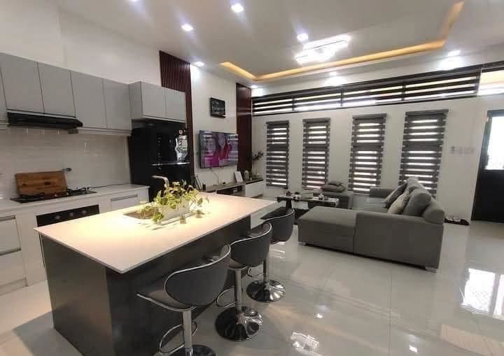 A living room with a couch and a kitchen with a large island in the middle.