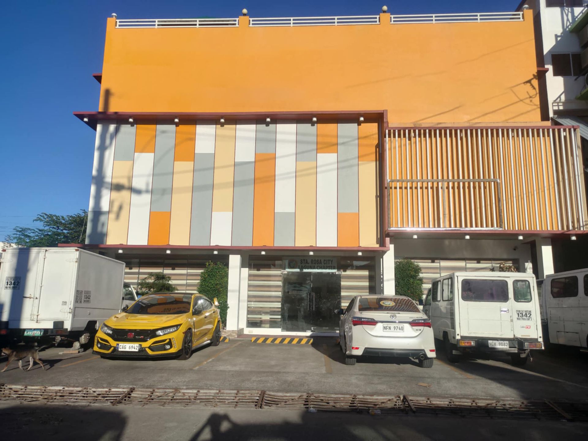A yellow car is parked in front of a building.