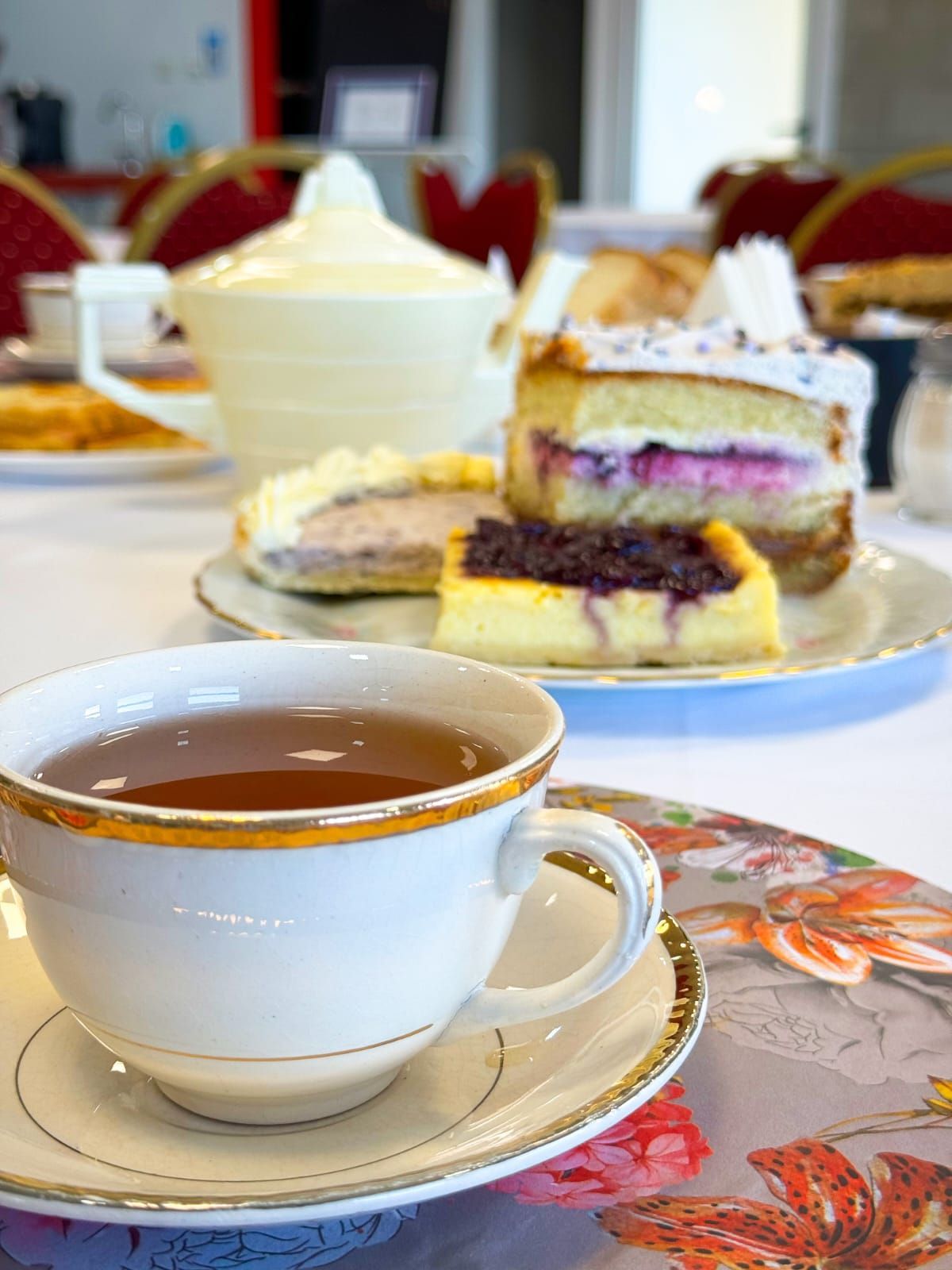 Una taza de té está sobre un platillo al lado de un plato de postres.