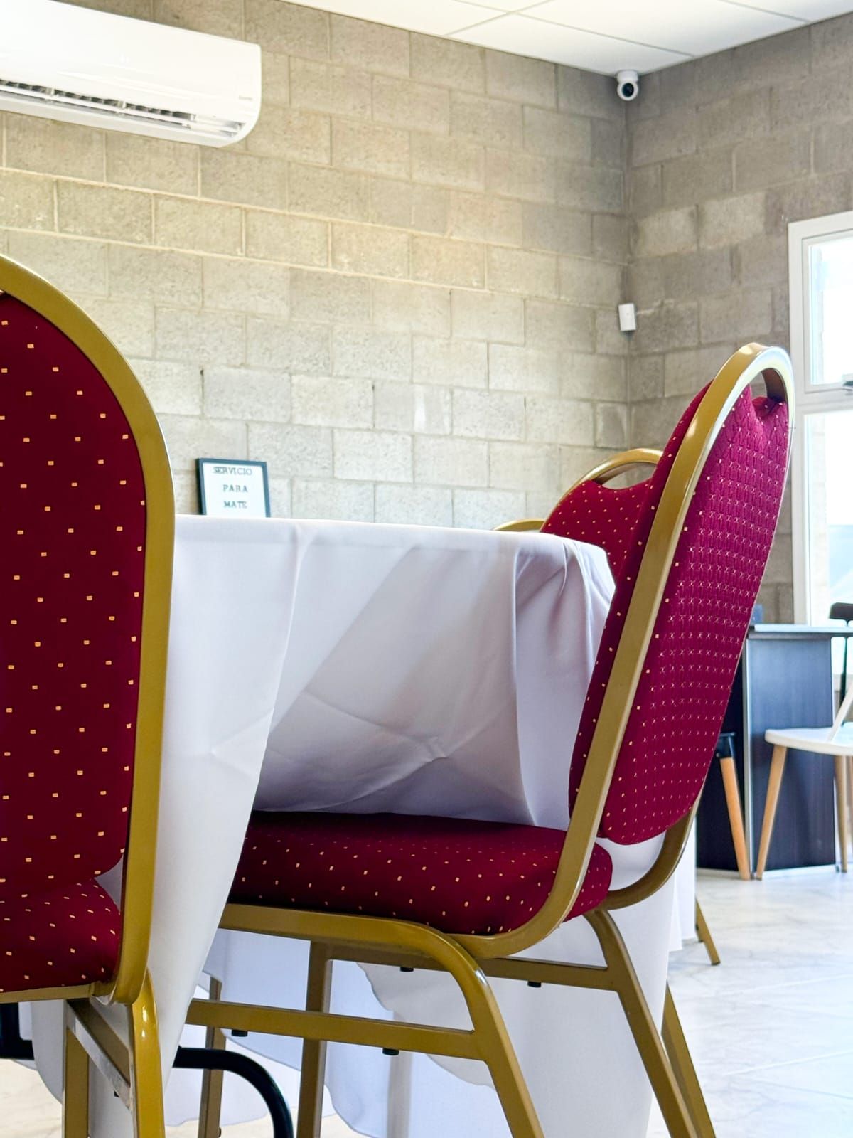 Una habitación con sillas rojas y un mantel blanco.