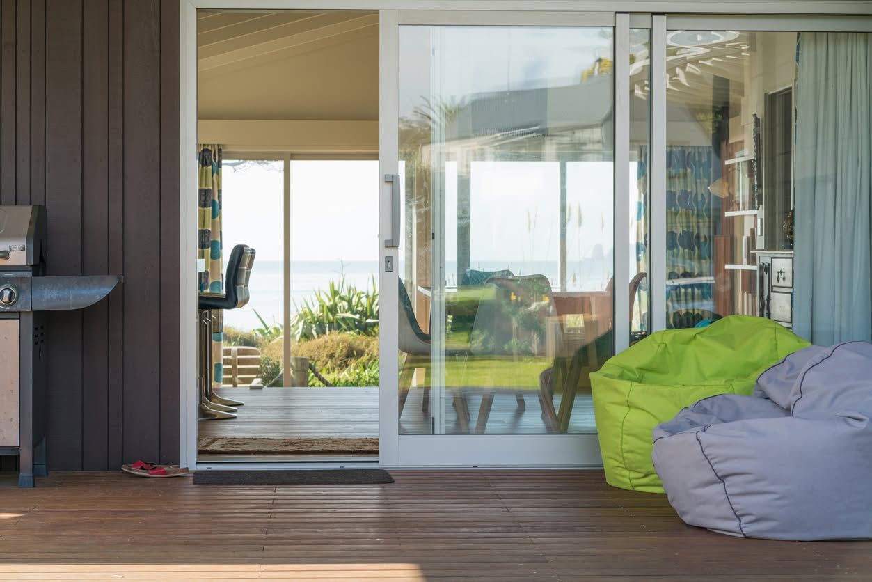 Patio with sliding glass doors, wooden deck, and green and gray bean bags overlooking the outdoors
