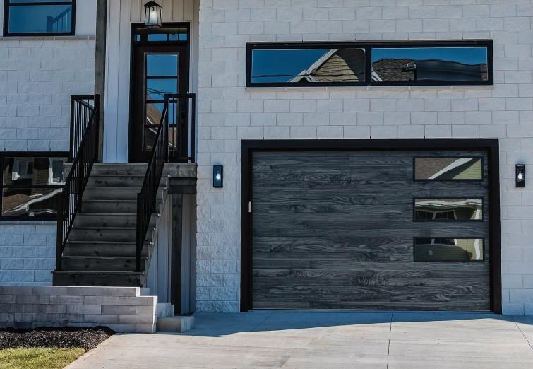 A white brick house with a wooden garage door and stairs leading up to it.