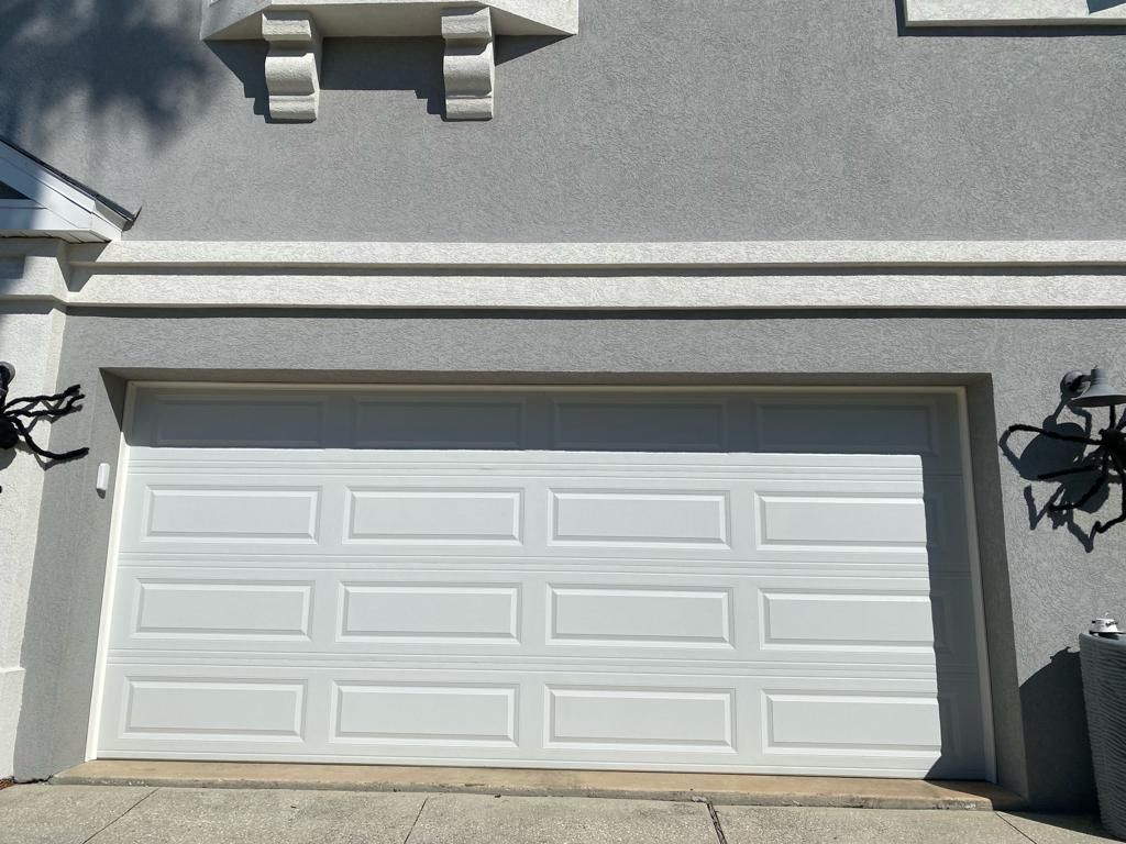 A white garage door is on the side of a house.