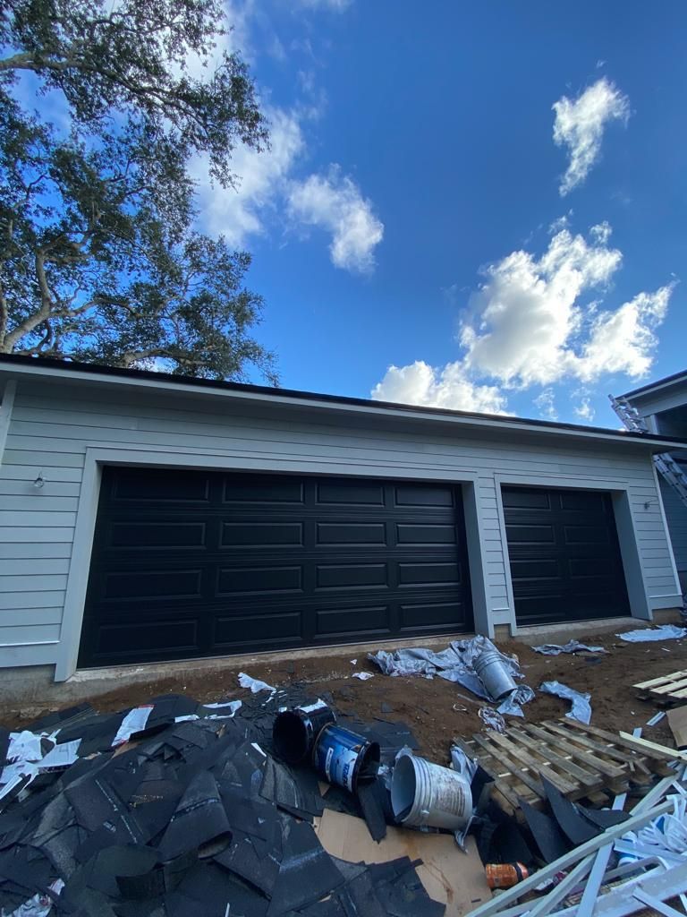 A black garage door is being installed on a house.