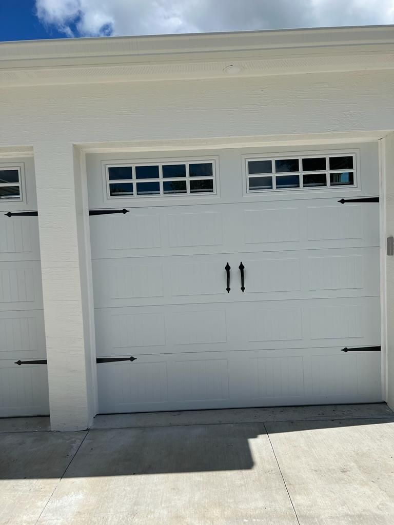 A white garage door with black handles and windows on a house.