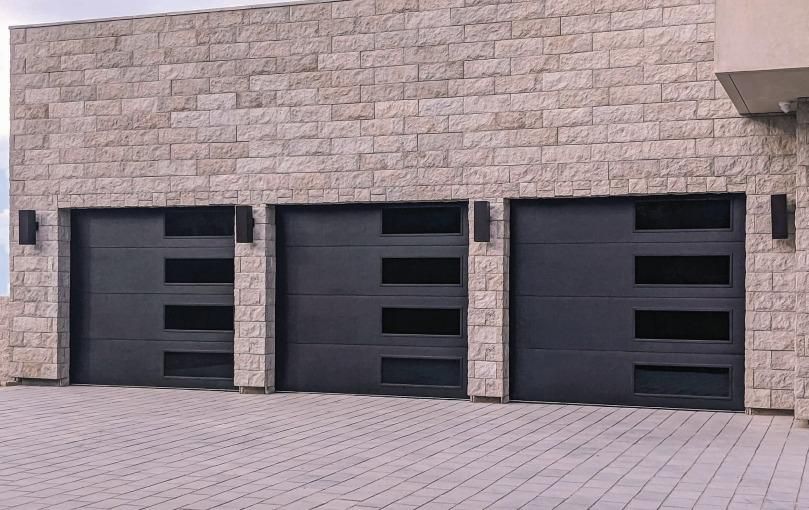 A brick building with three garage doors and a driveway.